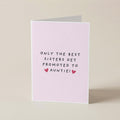 A folded greeting card standing upright on a light beige surface. The card is pale pink with the printed message 'ONLY THE BEST SISTERS GET PROMOTED TO AUNTIE!' in black text and two small pink hearts.