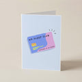 A folded greeting card standing upright on a beige surface, featuring a playful illustration of a credit card that reads 'NO SLEEP CLUB' in black text, with a blue-purple left half and a pink right half.