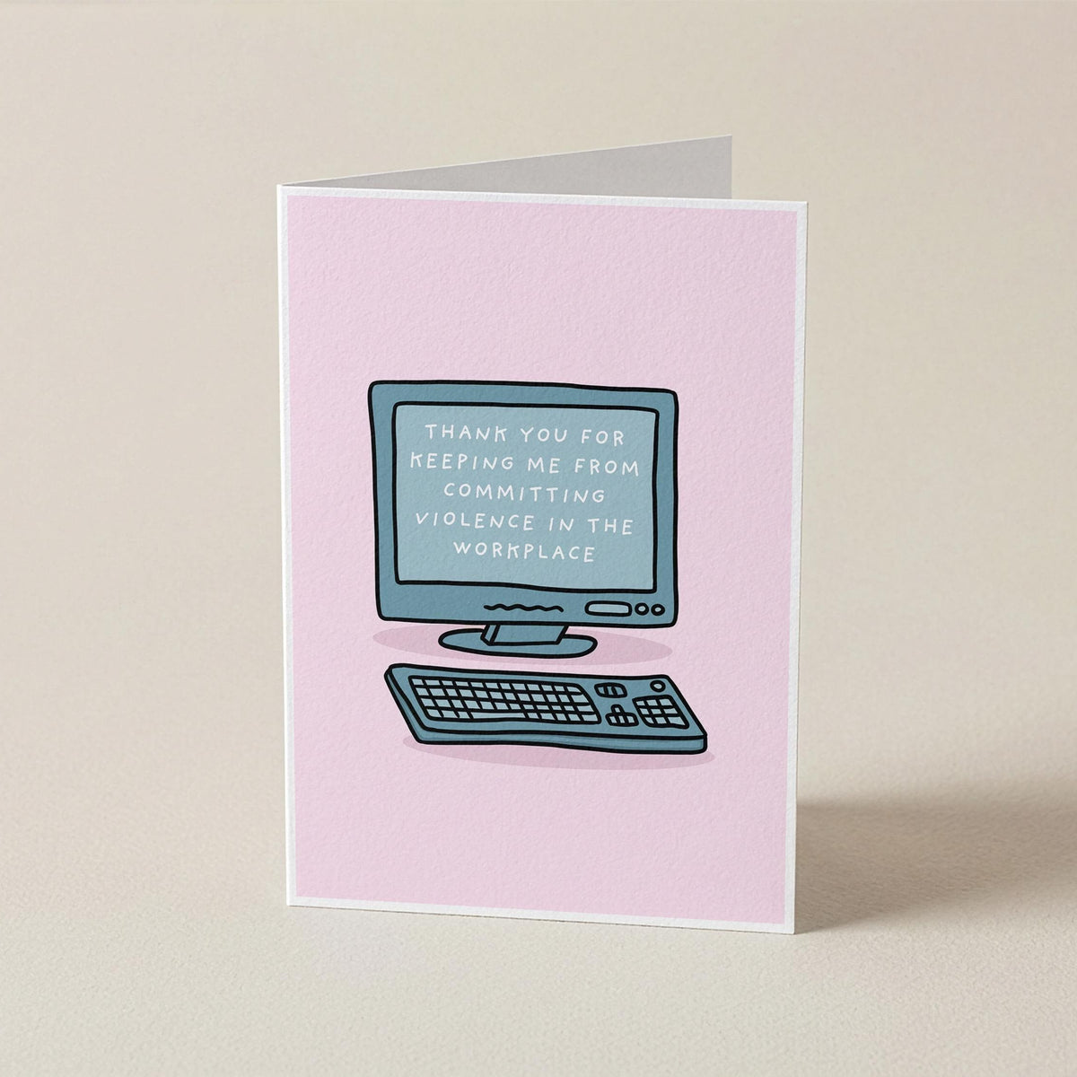 A pink greeting card standing upright on a beige surface, featuring a simple illustration of a computer and keyboard with the text 'THANK YOU FOR KEEPING ME FROM COMMITTING VIOLENCE IN THE WORKPLACE' on the screen.