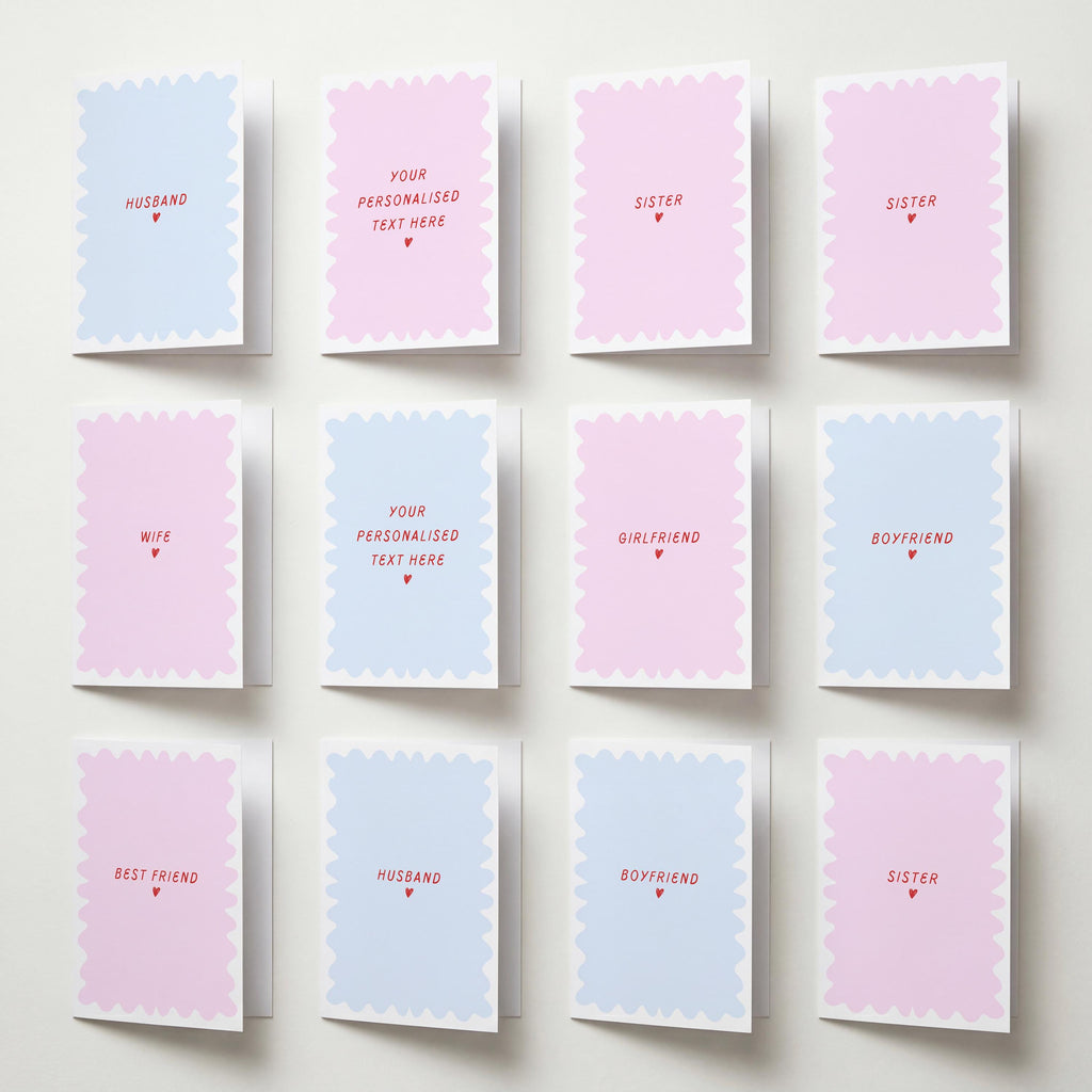 Twelve pastel greeting cards arranged in a 3x4 grid on a light wall. The cards have scalloped edges and are alternating between light pink and light blue, with red text placeholders such as 'HUSBAND', 'SISTER', 'WIFE', 'GIRLFRIEND', 'BOYFRIEND', 'BEST FRIEND', and 'YOUR PERSONALISED TEXT HERE'.