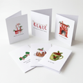 A set of illustrated Christmas greeting cards arranged on a clean white background. The cards show holiday scenes and messages including 'Merry Christmas!', 'sewing Christmas stockings', 'Tip the pot', 'Have a Christmas cookie', 'Have a nice Christmas', and 'Hot Tea at 6 pm'.