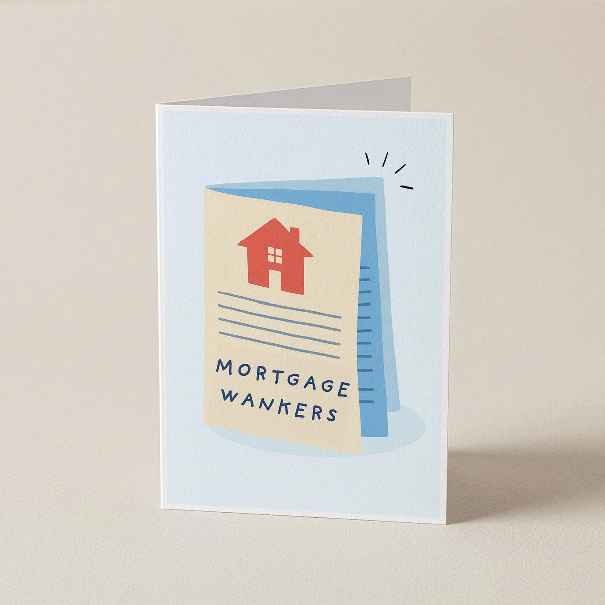 A folded greeting card standing upright on a light beige surface. The card features a minimalist illustration of a mortgage document with a red house icon and the text 'MORTGAGE WANKERS' in dark blue lettering.