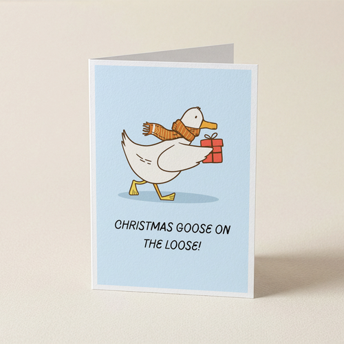 A folded greeting card standing upright on a light beige surface. The card features a white goose wearing a brown knit scarf and carrying a red gift box, with the text 'CHRISTMAS GOOSE ON THE LOOSE!' below on a pale blue background.